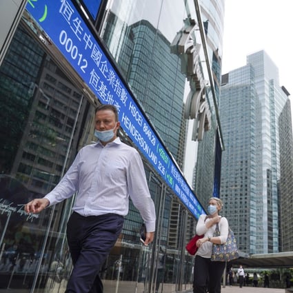 People walk past electronic tickers showing stock prices near the Exchange Square in Central, Hong Kong on October 7, 2021. Photo: Sam Tsang