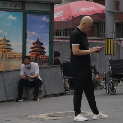 Chinese men use their smartphones on the streets of Beijing on August 22, 2021. Three months into a targeted campaign against the internet industry, China’s Ministry of Industry and Information Technology said scrutiny of the industry will deepen. Photo: AP