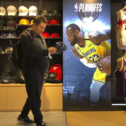A man shops for merchandise near a billboard of Los Angeles Lakers star LeBron James promoting the NBA playoffs at an NBA store in Beijing in October 2020. The NBA is returning to Chinese state television after a one-year absence. Photo: AFP
