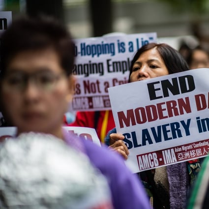 A woman holds a placard in a 2018 protest urging Hong Kong’s Immigration Department to review its accommodation and visa polices for foreign domestic helpers. There are around 370,000 such workers in the city. Photo: AFP