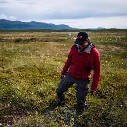 Bubbles of methane rise to the surface of the water at Stordalen mire in northern Sweden, as Keith Larson, head of the Abisko Scientific Research Station, demonstrates the effects of the melting permafrost beneath the marshy land on August 24, 2021, near the village of Abisko, in Norrbotten County, Sweden. – In the Arctic in Sweden's far north, global warming is happening three times faster than in the rest of the world. Storflaket and the nearby Stordalen sites are key centres of research in Europe into the effects of climate change on permafrost. The methane is released as the permafrost melts. (Photo by Jonathan NACKSTRAND / AFP)