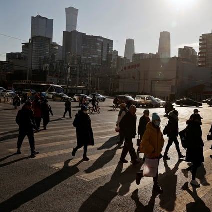 People cross a street during morning rush hour in front of the skyline of the central business district in Beijing in December 2020. Photo: Reuters