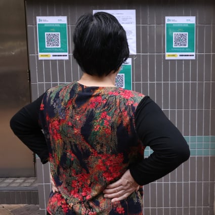 A woman looks at ‘Leave Home Safe’ QR codes posted at the Tai Po Hui wet market. Photo: K. Y. Cheng