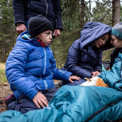 The Massini family from Syria are comforted by an activist while awaiting transport in the forest near the east Polish town of Kleszczele in October. Thousands of migrants, mostly from the Middle East have crossed or tried to cross from Belarus since the summer. Photo: AFP