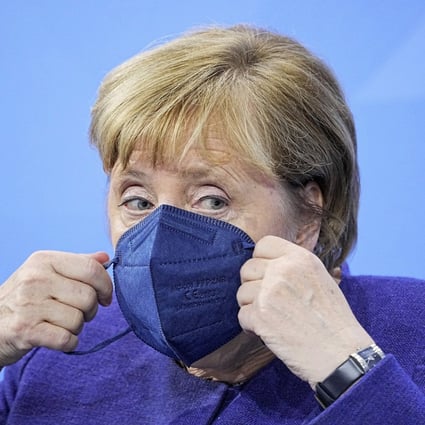 German Chancellor Angela Merkel puts on a face mask as she attends a news conference in Berlin on Thursday. Photo: AP
