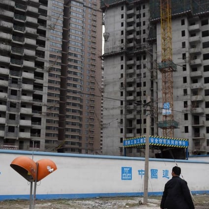 Two men walk past a construction site for apartment buildings in Beijing as internet-based rivals pose an increasing challenge to traditional property companies in the market. Photo: AFP
