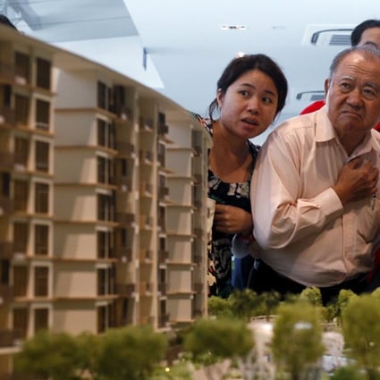 Prospective buyers look at a model of an upcoming suburban private condominium development during its launch in Singapore. Prices of Singapore's private homes fell for the eighth straight quarter due to government cooling measures. Photo: Reuters