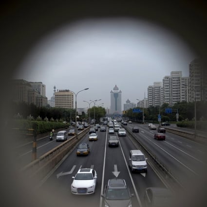 Traffic, shot through an opening, moves along a street in the financial district of Beijing. Photo: Bloomberg