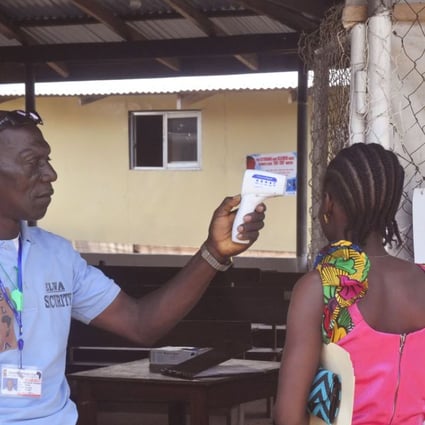A unidentified family member, right, of a 10-year old boy that contracted Ebola, has her temperature measured by a health worker before entering the Ebola clinic in Monrovia, Liberia. Photo: AP