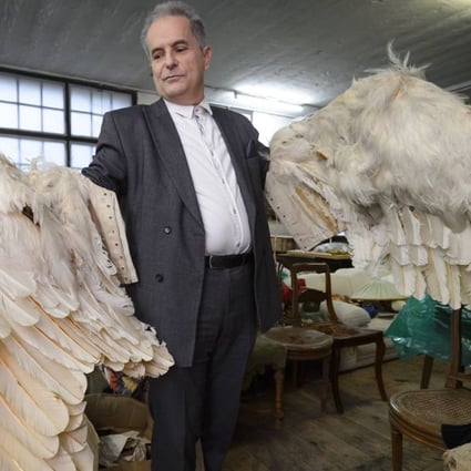 Swiss author Pierre Smolik poses with crafted wings covered with swan feathers made for a final film by comic actor and filmmaker Charlie Chaplin that was never completed. Photo: AFP