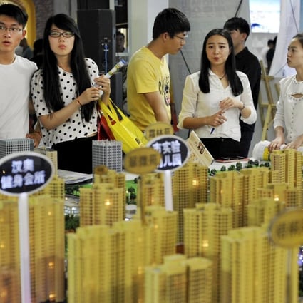 Sales representatives talk to potential buyers in front of a model of a residential complex at a real estate exhibition in Wuhan, Hubei province, China. Photo: Reuters