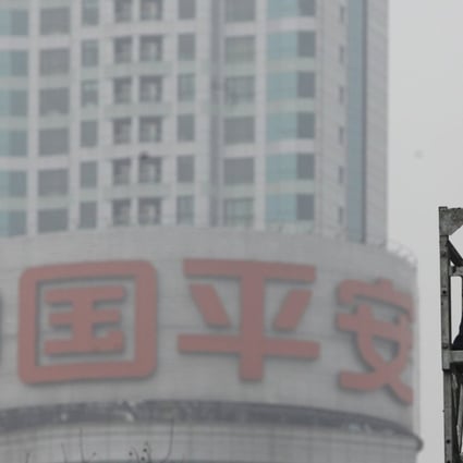 A worker cleans the windows of a building in front of the Ping An Insurance building in Shanghai. Photo: Reuters