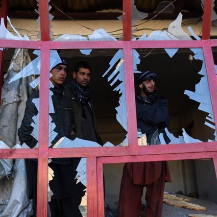 Afghans peer through the broken windows of a bakery at the site of a suicide car bomb blast near the international airport in Kabul on Monday that killed one person. Photo: AFP