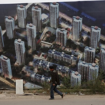A man walks past a wall at a construction site for a new residential compound in Tianjin’s Binhai new district. Photo: Reuters
