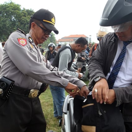 Police officers checked motorcyclists at a security check point in Bali, Indonesia. Photo: AP