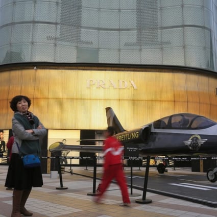 Shoppers look at a Breitling model aircraft on display outside a Prada store in Beijing. Photo: EPA