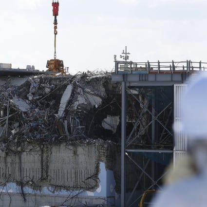 A member of the media, wearing a protective suit and a mask, looks at the damaged reactor building at the Fukushima Daiichi nuclear power plant. Photo: Reuters