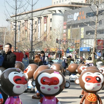 Citizens pose for photos among monkey figurines in front of a shopping mall in Jinan, capital of Shandong Province. Property consultants say neighbourhood shopping malls in the suburbs have become bright spots in the industry. Photo: Xinhua