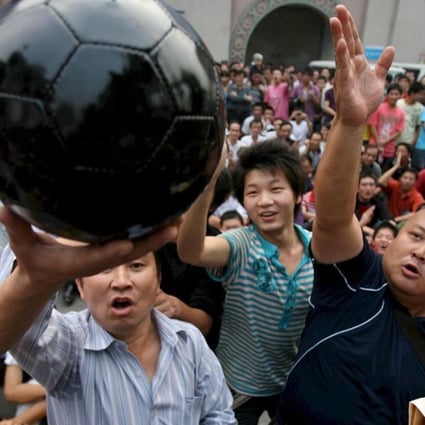 Soccer fans beat a black football which symbolises dark Chinese football industry as they protest outside a stadium in downtown Wuhan city in 2008. Despite a clampdown on corruption since then, problems still remain. Photo: EPA