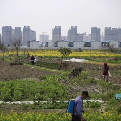 A farmer works on a farm in front of a construction site of new residential buildings in Shanghai on March 21, 2016. Photo: Reuters