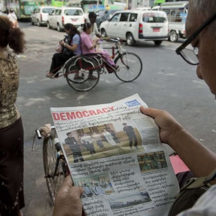 A Myanmar man reads a newspaper reporting on the handover of government in Yangon, a day before a new civilian government overseen by democracy icon Aung San Suu Kyi took office. Photo: AFP