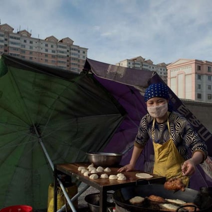 A street food vendor cooks food nearby the Jiuquan Iron & Steel (Group) factory complex as the sun rises over the city of Jiayuguan, some 2,000 km (1,250 miles) west of Beijing on April 22, 2016. Photo: AFP