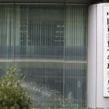 A gardener waters plants outside the China Securities Regulatory Commission headquarters in Beijing. Photo: EPA