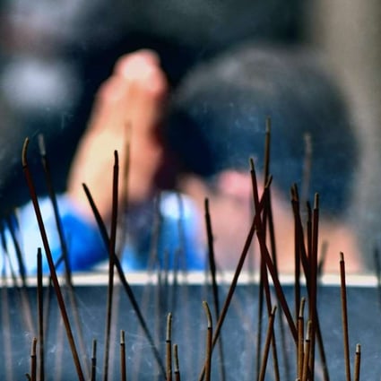 A man prays behind burning incense at Lung Shan Temple in Taipei. Some temples are asking worshippers to stop burning incense and paper offerings to reduce air pollution. Photo: AFP