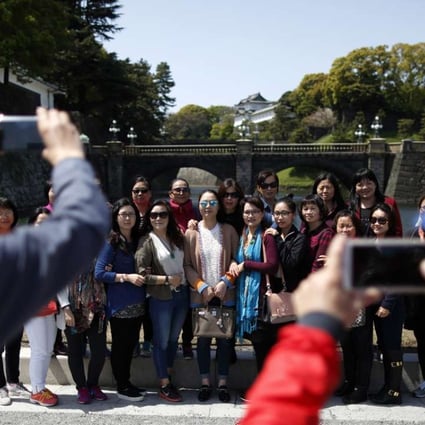 Tourists from China pose for a group photograph outside the Imperial Palace in Tokyo, Japan, on Friday, April 15, 2016. The Japan National Tourism Organization's monthly statistics on the number of foreign visitors to Japan will be published on Wednesday. Photo: Bloomberg