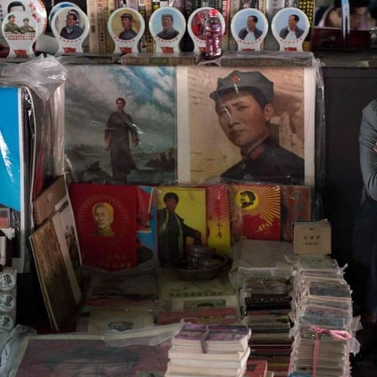 A vendor takes a nap next to posters showing Mao Zedong (centre) and Xi Jinping (left) at a market in Beijing. Photo: AFP