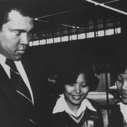 Muhammad Ali playfully glares at two women security guards as they check his travel documents at Hong Kong’s Kai Tak airport in December 1979 while on his way to mainland China. Photo: AP