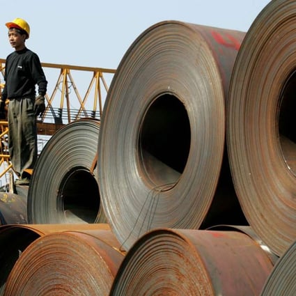 A worker stands on a stack of rolled steel, shipped from the Baosteel factory in Shanghai, on a dock at Guangzhou, Guangdong province. Photo: Greg Baker, AP