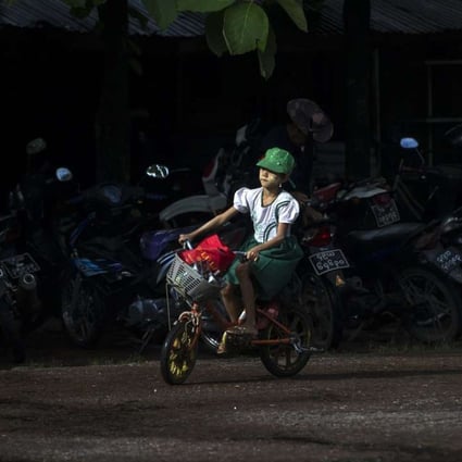 A schoolgirl rides her bike in Yangon. In Myanmar, just one fifth of the roads are paved. Photo: AFP