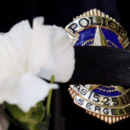 A Dallas police sergeant wears a mourning band and flower on his badge during a prayer vigil, one day after a lone gunman ambushed and killed five police officers at a protest decrying police shootings of black men, in Dallas, Texas, July 8, 2016. Photo: Reuters