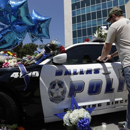 Michael O'Mahoney, a former police officer, places his patch on a make-shift memorial at the Dallas police headquarters, after five police officers are dead and several injured following a shooting in downtown Dallas. Photo: AP