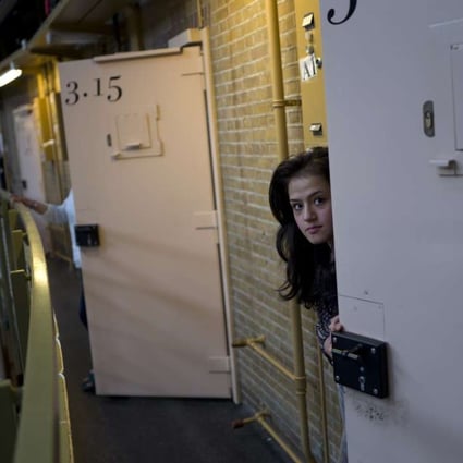 Afghan refugee Shazia Lutfi, 19, peeks through the door of her room at the former prison of De Koepel in Haarlem, Netherlands. Photo: AP