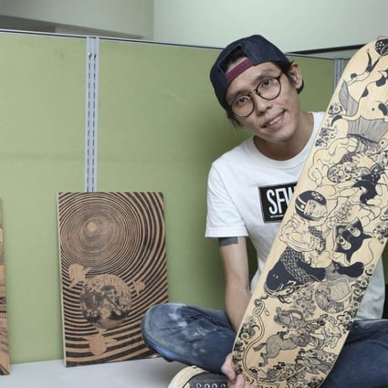 Jan Curious with one of his repurposed skateboards and two illustrations, part of the SFW exhibition in Sai Ying Pun.