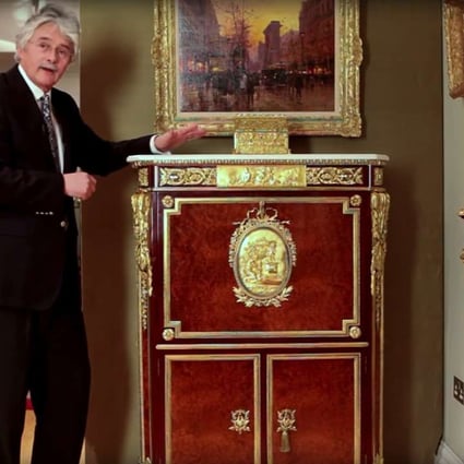Furniture historian Christopher Payne poses next to a unique secretaire abattant, made as an exact copy of one in the Wallace Collection of art and antiques on display in London.