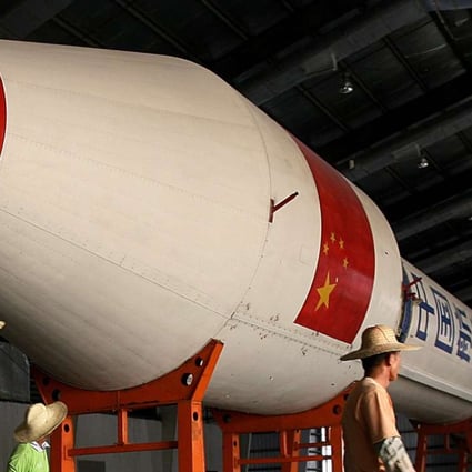 Chinese workers walk past a Long March Rocket. Photo: AFP