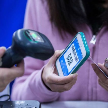 A customer with a barcode on her Apple iPhone scanned by a cashier for payment through Alipay. Photo: Martin Chan