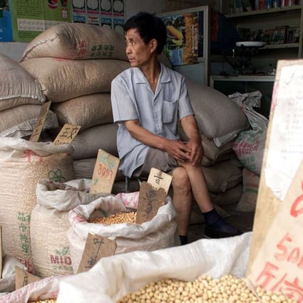 A shopowner waits with sacks of corn and soya beans at the Baoding Seed Market in Hebei province. Photo: AP