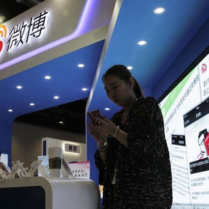 A woman browses her smartphone near a display booth at the Global Mobile Internet Conference in Beijing. Photo: AP