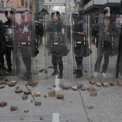 Police stand guard as protesters throw bricks during the Mong Kok riot in February. Photo: AP