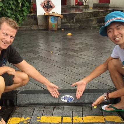 Doug Woodring and environmentalist Hiromasa Suzuki install a tile designed by Chen Huaxian, in Stanley.