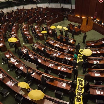 Pan-democratic lawmakers file out of the Legislative Council chamber holding yellow umbrellas and banners calling for genuine universal suffrage ahead of the chief executive’s policy address in January 2015. Photo: EPA