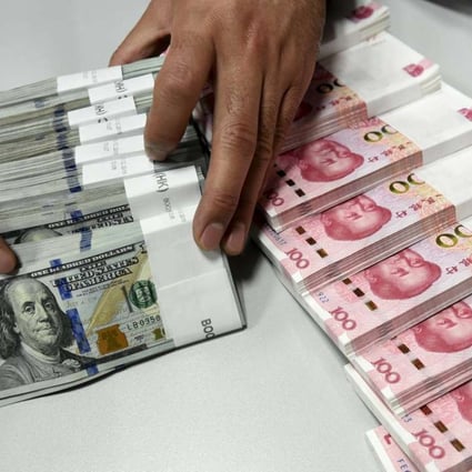 A clerk counts Chinese yuan and US dollar banknotes at a bank in China. Photo: Reuters
