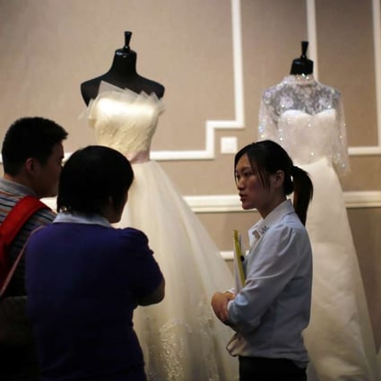 A couple talk to a vendor at a wedding dress stand during a wedding exhibition in downtown Shanghai. Photo: Reuters