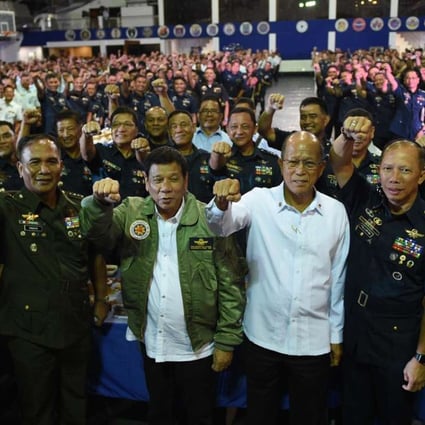 Philippine President Rodrigo Duterte, centre, wearing an air force jacket given to him as a gift, poses with defence secretary Delfin Lorenzana, fourth right, and military chief General Ricardo Visaya, third left. Photo: AFP