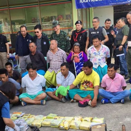 Thai police officers inspect confiscated weapons and drugs after a raid operation leading to the arrest of alleged Golden Triangle drug lord Laota Sanli (second row, left, wearing black) and others, including his family members, at a petrol station in Mae Ai district, Chiang Mai Province. Photo: EPA