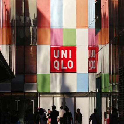 People stand outside a Uniqlo shop in Beijing in this August 24, 2013 file photo. Fast retailing, operator of the Uniqlo clothing chain, said on January 27, 2014 it plans to list its shares on the Hong Kong exchange on March 5 as it aims to boost its presence in the region and expand its investor base globally. Picture taken August 24, 2013. REUTERS/Petar Kujundzic/Files (CHINA - Tags: BUSINESS)